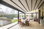 Pergola R128 Pergotesa BT Group con chiusure vetrate e area living outdoor