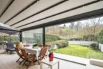 Pergola R128 Pergotesa BT Group con vetrate panoramiche e area relax outdoor
